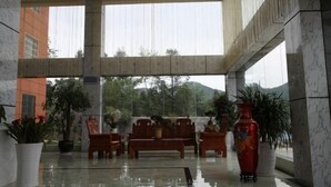 Un vestíbulo espacioso con techo alto, columnas de mármol y una zona de estar con muebles de madera.