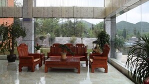 Un hallo espacioso con suelo de mármol, muebles de madera y amplias ventanas que ofrecen vistas a zonas verdes y colinas.