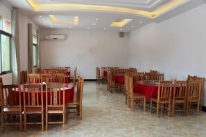 A conference room with multiple round tables and chairs, arranged in rows. - Junlong Holiday Hotel (Dafang)