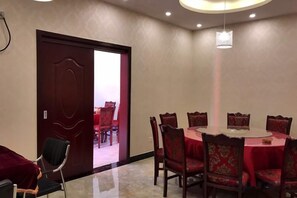 Un salón de conferencias con una mesa redonda, sillas rojas y una puerta que da a otra habitación.