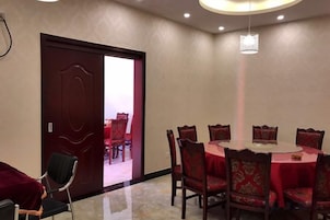 Un salón de conferencias con una mesa redonda, sillas rojas y una puerta que da a otra habitación.