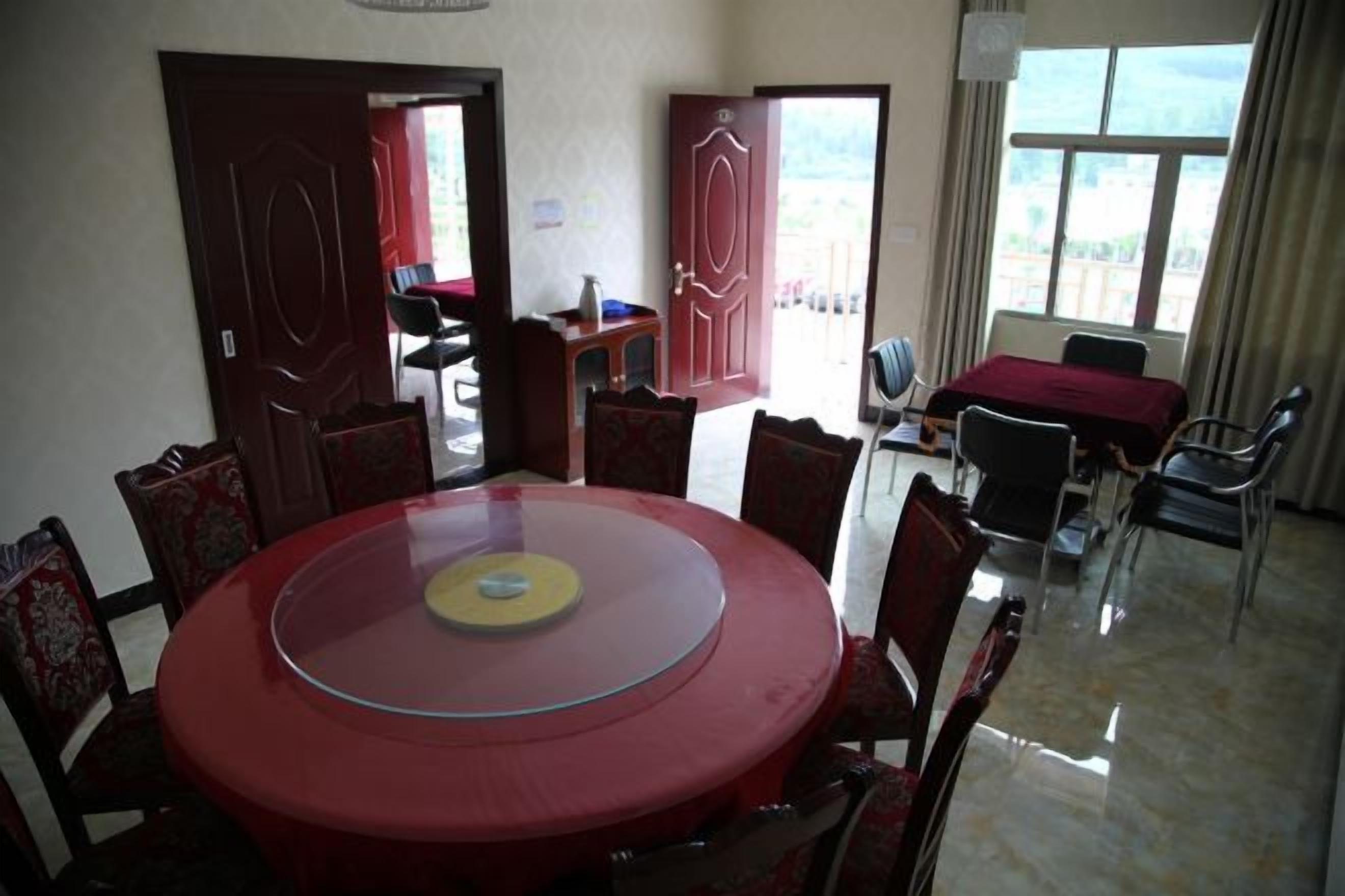 A conference room with a round table, chairs, and a red tablecloth. There are doors leading to other areas.