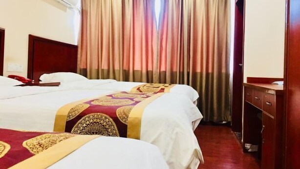 Camera d'albergo con due letti, una testiera in legno, una scrivania e un armadio.