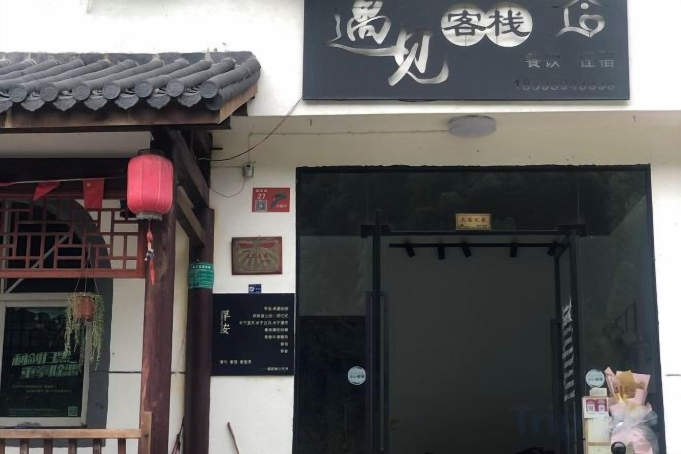 A traditional Chinese building with a tiled roof, a black entrance gate, and a signboard with Chinese characters.