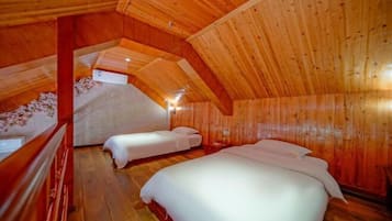 Un interior de madera con dos camas, techo de madera y una pequeña mesa.