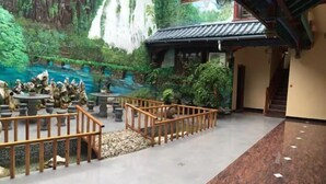 Un hall con un mural de una cascada y follaje, barandilla de madera y suelo de baldosas.
