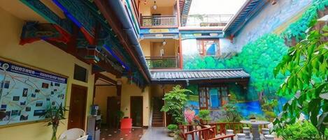 A courtyard with a wooden floor, potted plants, and outdoor seating.