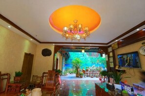 A hotel lobby with a chandelier, a reception desk, and a large aquarium. - Anyixuan Inn (Libo)