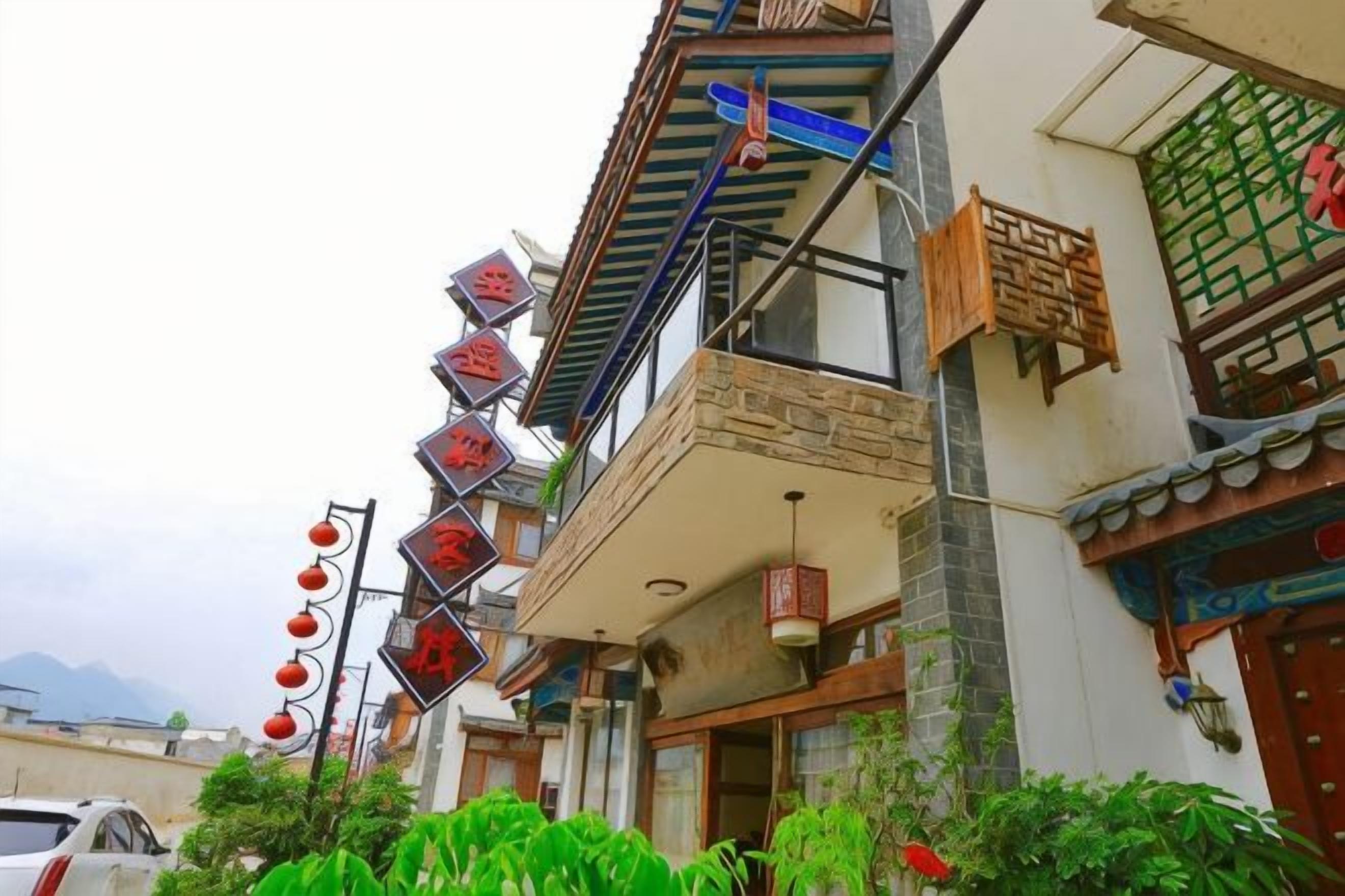 A traditional building with a balcony, signage, and a car parked in front.