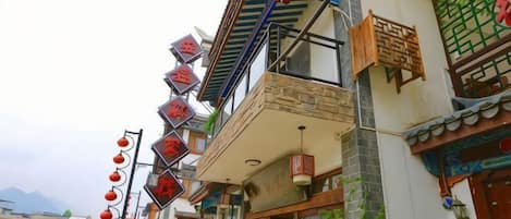 A traditional building with a balcony, signage, and a car parked in front.