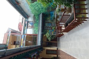 A multi-level building with balconies, staircases, and a variety of plants. - Anyixuan Inn (Libo)