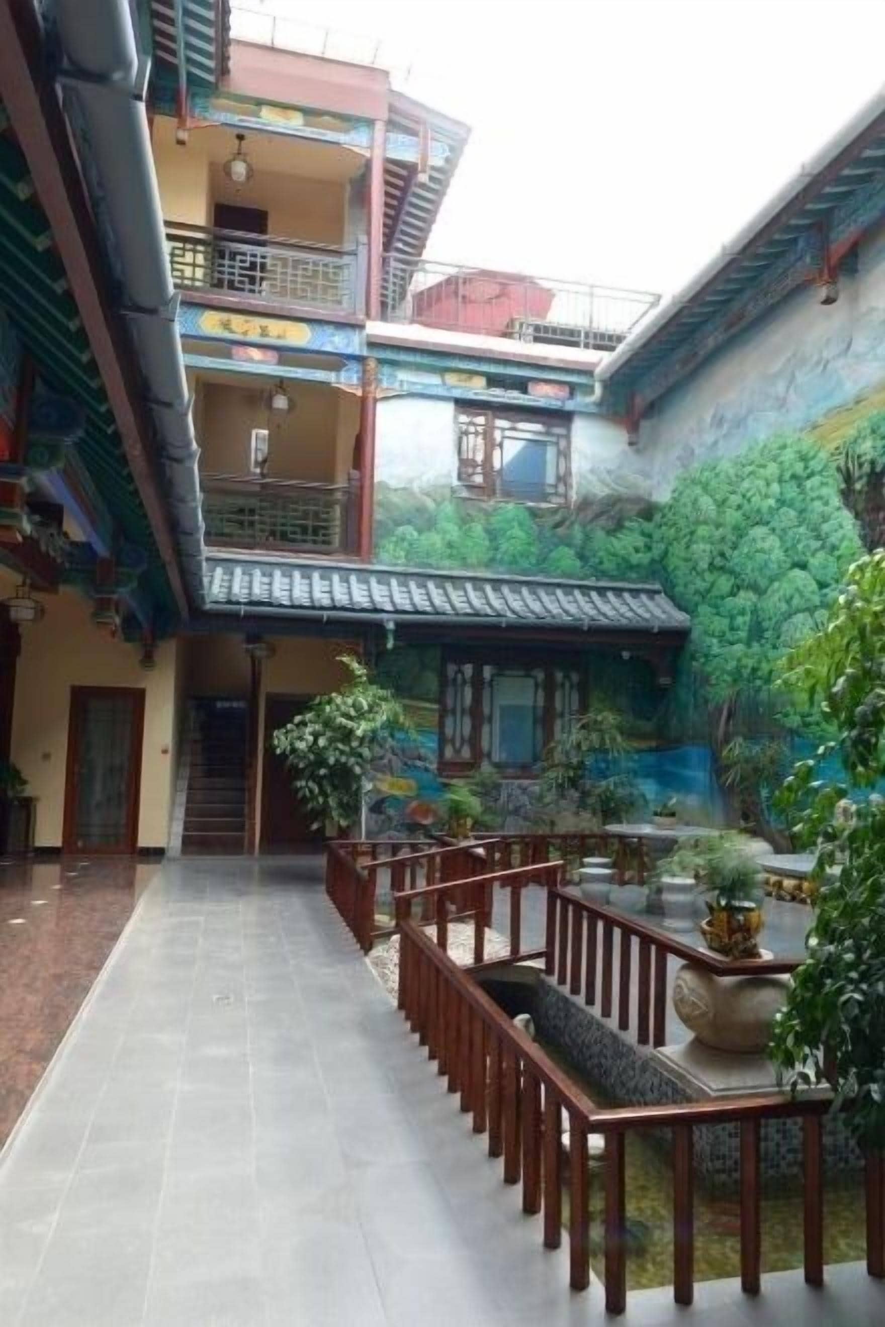 A courtyard with a traditional building, a staircase, and a seating area with plants.