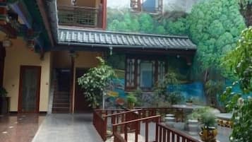 A courtyard with a traditional building, a staircase, and a seating area with plants.