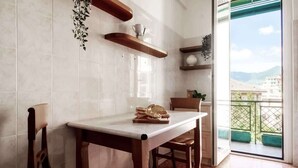 A kitchen with a marble countertop, wooden chairs, and a view of the outdoors through a glass door. - OMAR'S HOUSE - Affitti Brevi Italia (Rapallo)