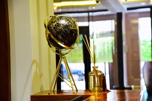 A globe on a stand, a glass vase with a candle, and a window with a view of greenery.