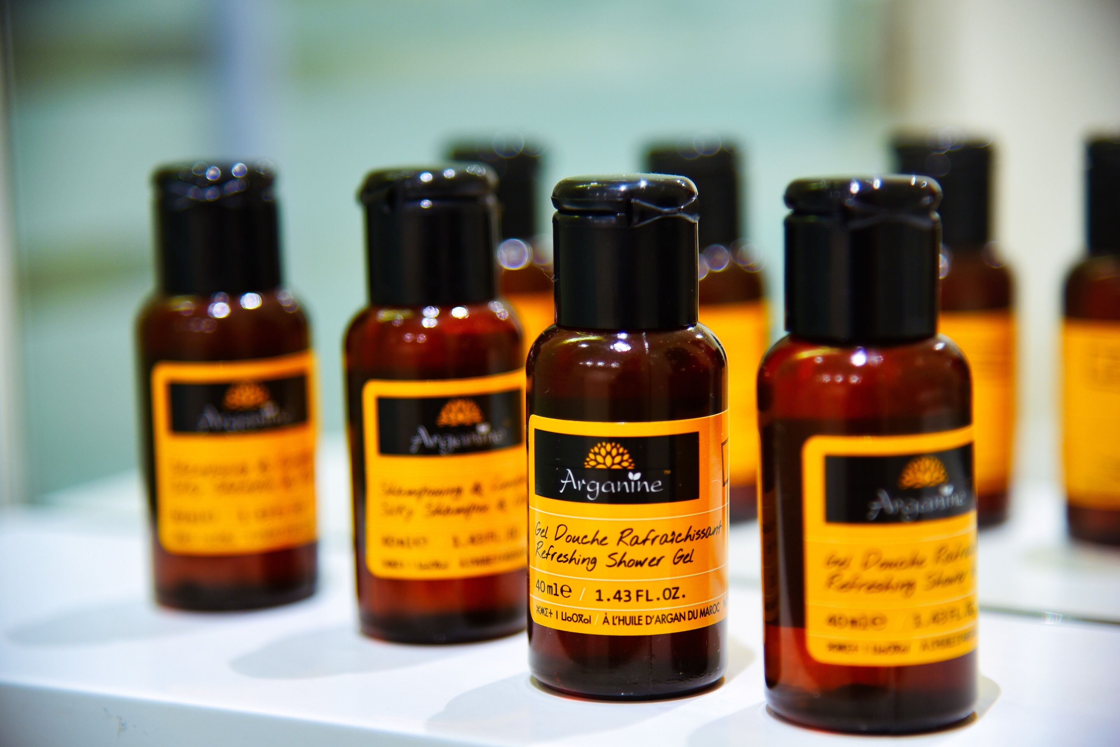 Several bottles of Arganine shower gel on a shelf.