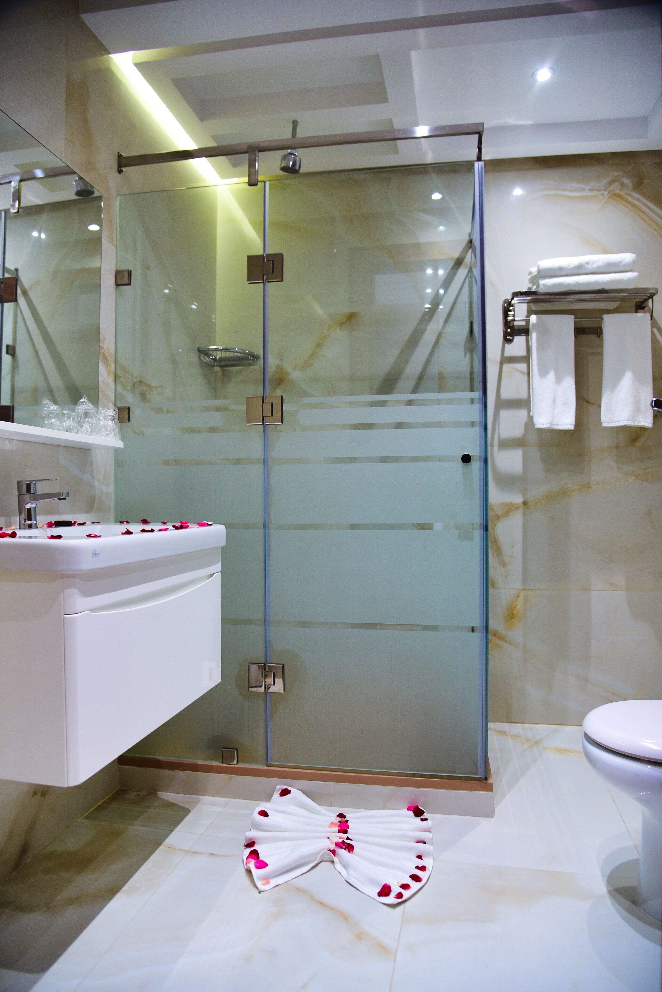 Een moderne badkamer met een douchecabine van glas, een wit wastafelmeubel en een toilet.
