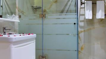 Een moderne badkamer met een douchecabine van glas, een wit wastafelmeubel en een toilet.