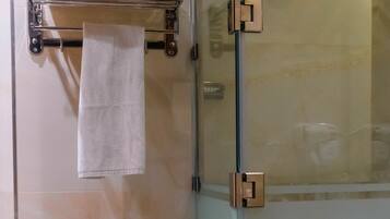 Ein Badezimmer mit Duschkabine aus Glas, einem Handtuchhalter mit weißem Handtuch und einer Glastür.