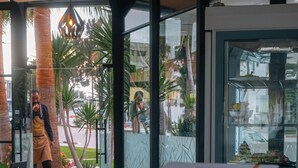 Interior de un restaurante con un separador de vidrio, vistas al exterior y un menú sobre la mesa.