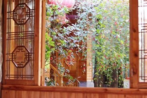 Un pasillo de madera con una verja tradicional y un arco de bambú sobre ella.