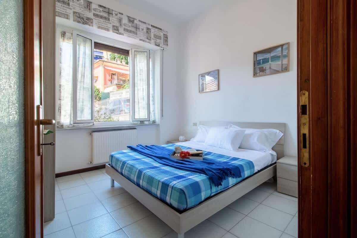 Une chambre à coucher avec un lit, une fenêtre, un radiateur, une petite table de chevet et une porte.