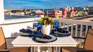 Ein Balkon mit Tisch, blauem Servietten, Blumen in einer Vase und Weingläsern.