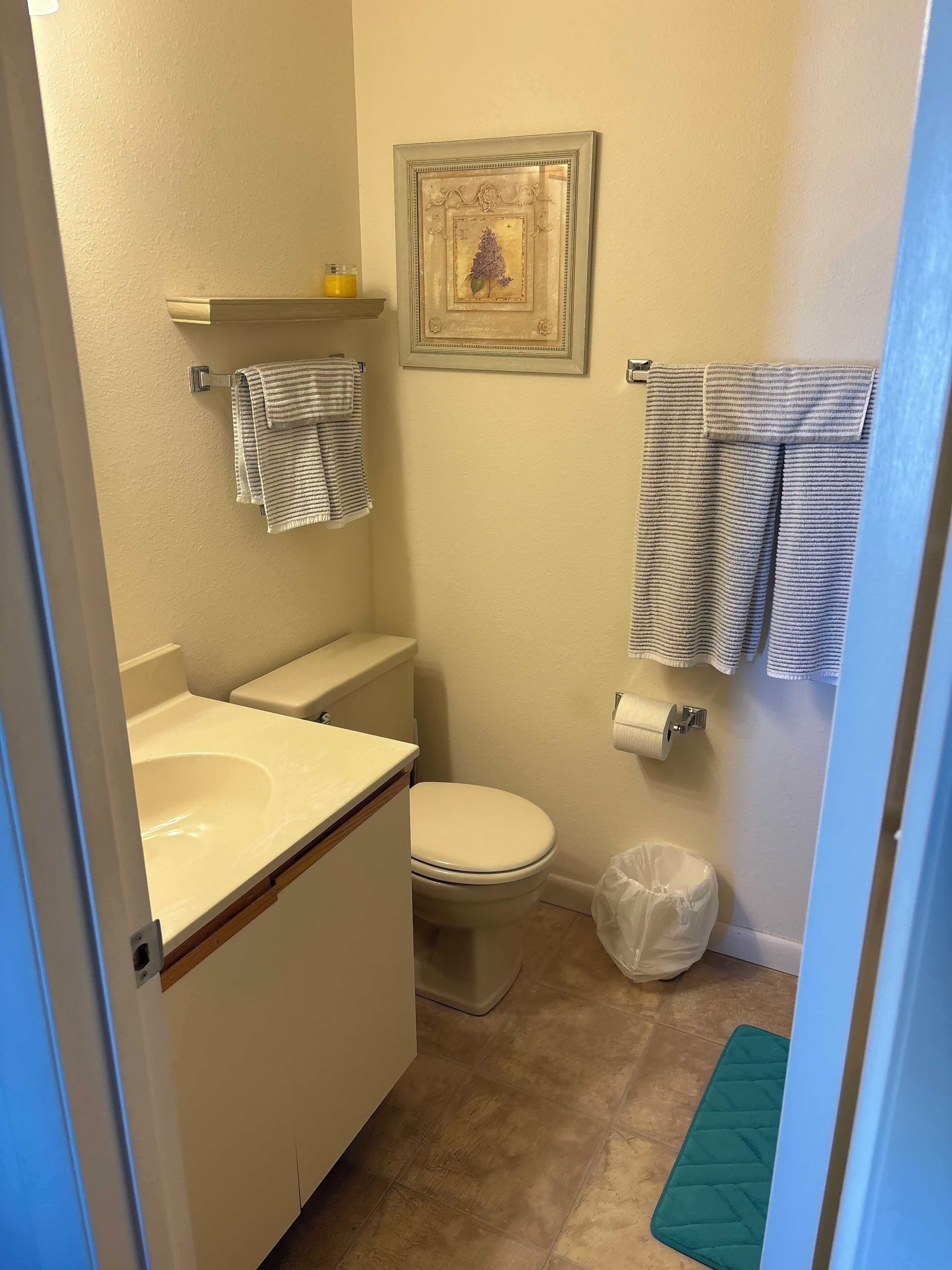 A small bathroom with a toilet, sink, and a framed picture on the wall.