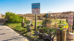 Ein Straßenschild für 52nd Street Dune Crossing mit einem Rauchverbotsschild, einem Parkverbotsschild und einem Osterdekoration.