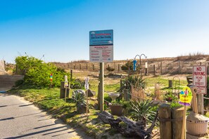 A road sign for 52nd Street Dune Crossing with a 'No Smoking/Vaping' sign, a 'No Parking' sign, and a 'Happy Easter' decoration.