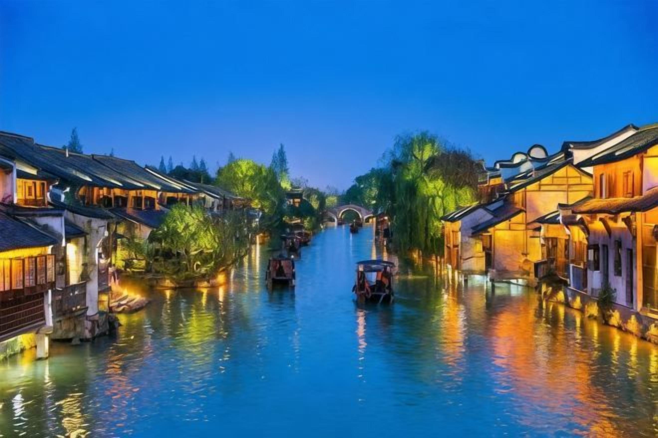 A canal with traditional buildings on either side, a bridge in the distance, and a boat in the water.
