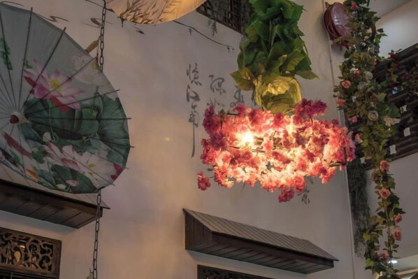 A room with a decorative wall, a hanging floral arrangement, and a ceiling fan.