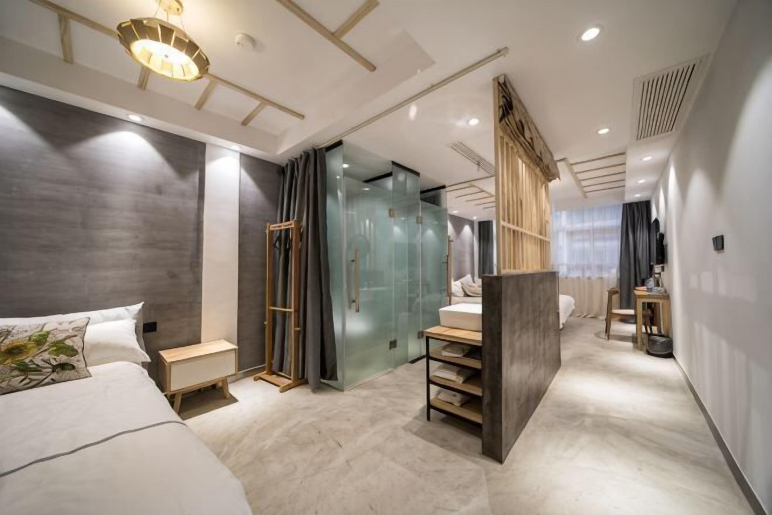 Una habitación de hotel moderna con cama, tocador, zona de ducha y vestidor.