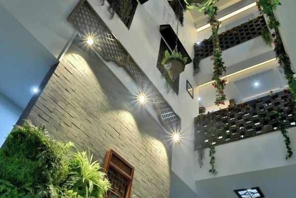 A multi-level interior with brick walls, hanging plants, and recessed lighting.