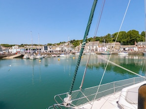 A harbor with boats docked, a sailboat in the foreground, and buildings along the shore. - Piran Lodge (Padstow)