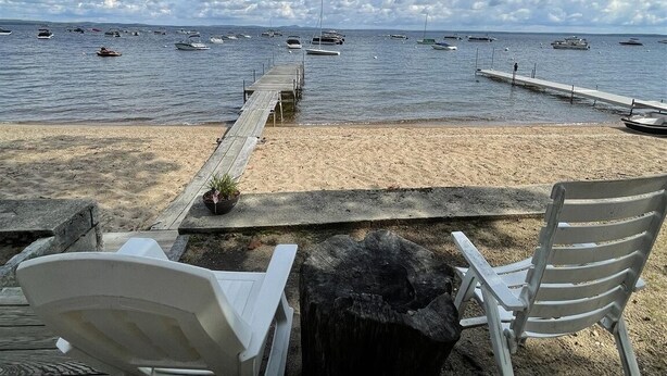 A beach with two white lounge chairs and a wooden pier extending into the water. - Clearview Limit 6 4 Bedroom Villa by RedAwning (Sebago)