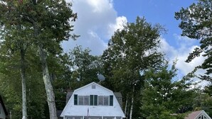 A wooden dock leading to a white house with a porch, surrounded by trees and a sandy beach. - Clearview Limit 6 4 Bedroom Villa by RedAwning (Sebago)