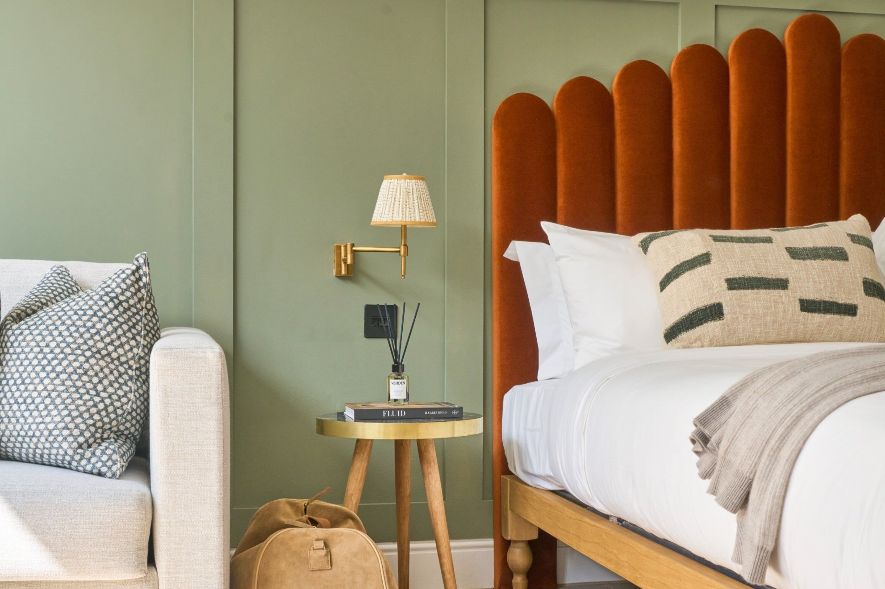 A neatly arranged bedroom with a wooden bed, a side table with a lamp, and a small bookshelf.