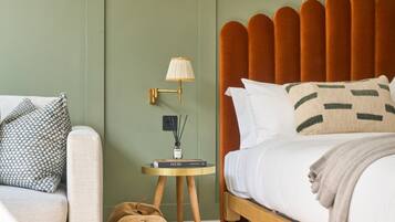A neatly arranged bedroom with a wooden bed, a side table with a lamp, and a small bookshelf.