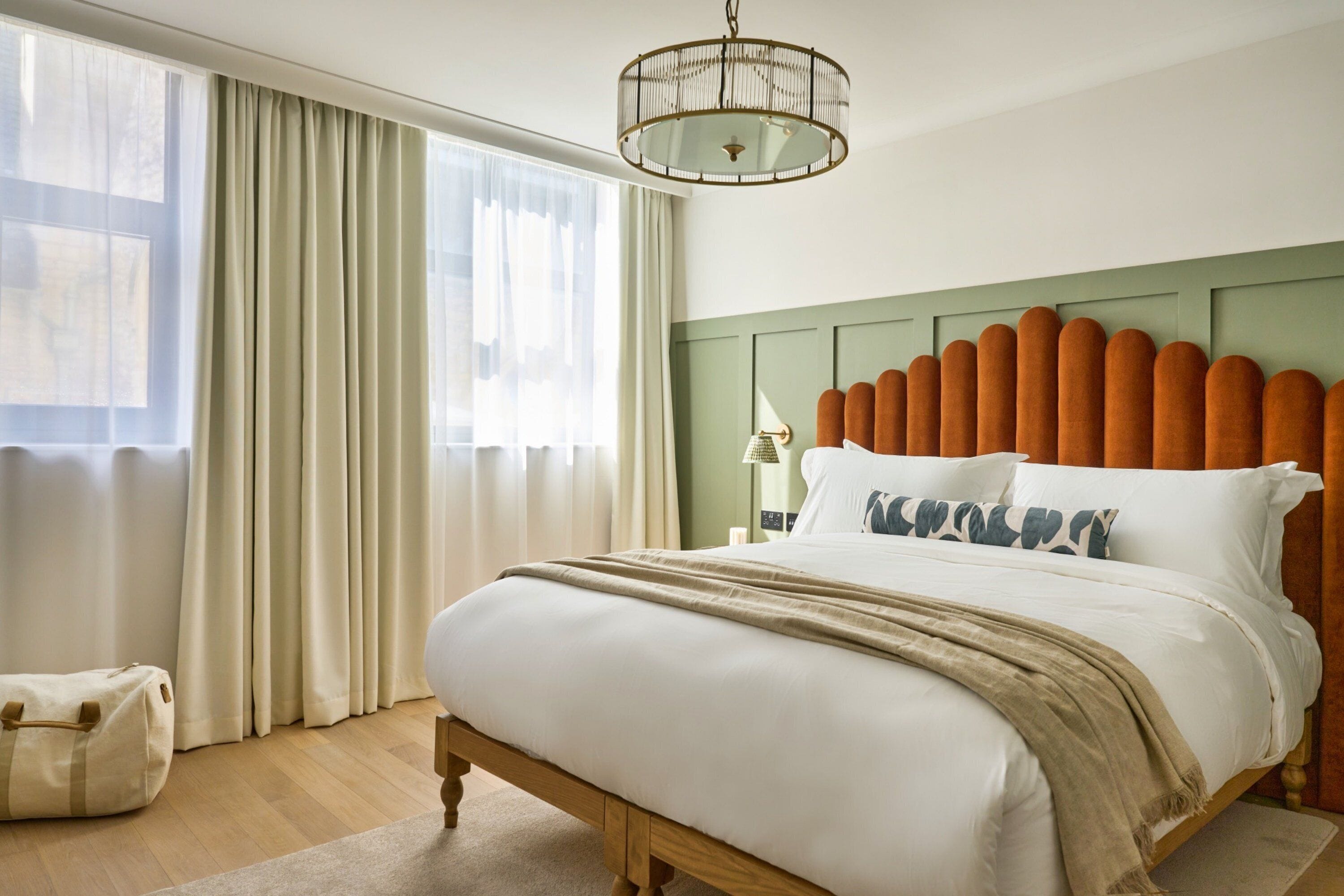 A neatly made bed with a wooden headboard, a bedside lamp, and a window with curtains.
