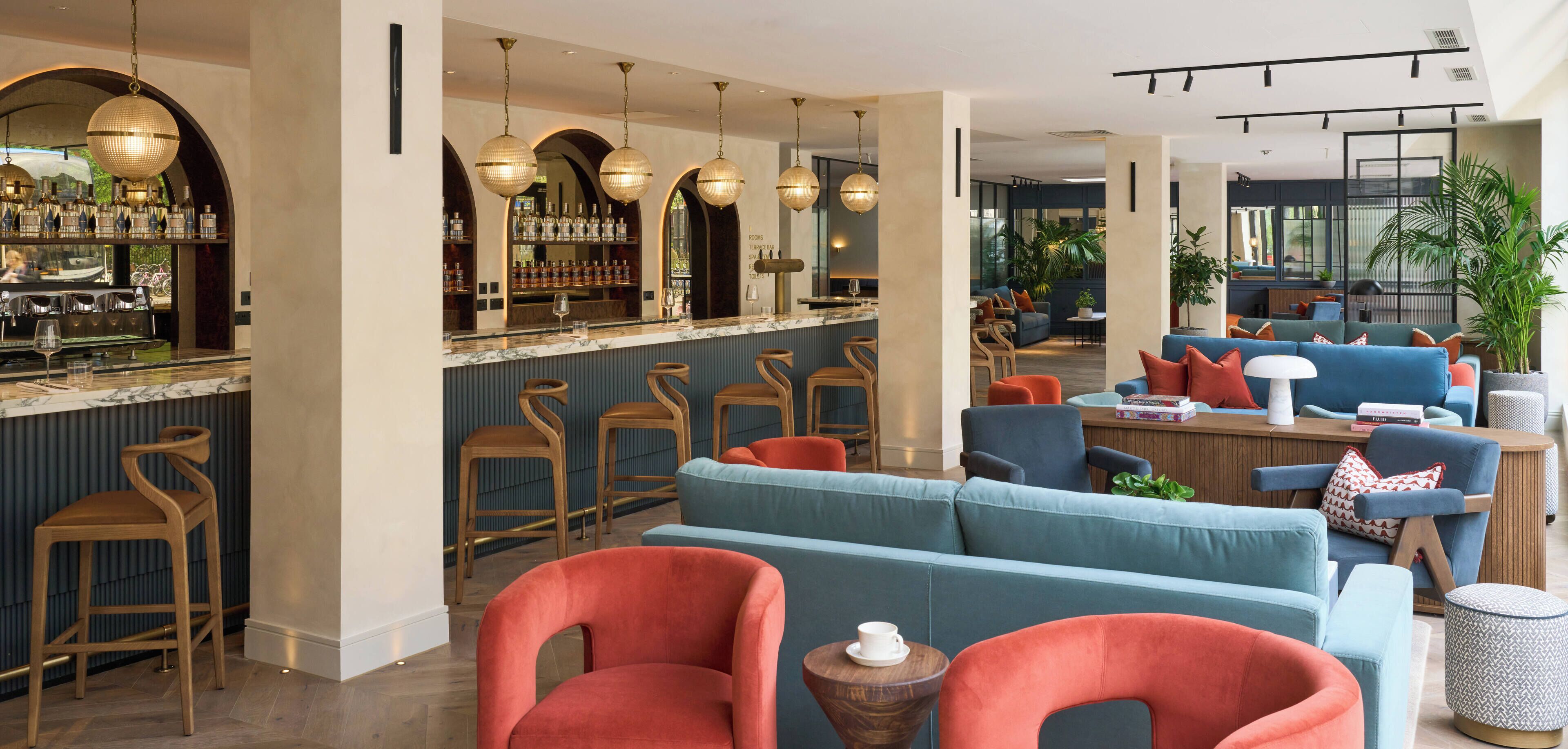 A modern bar area with a marble countertop, wooden bar stools, and hanging spherical light fixtures.