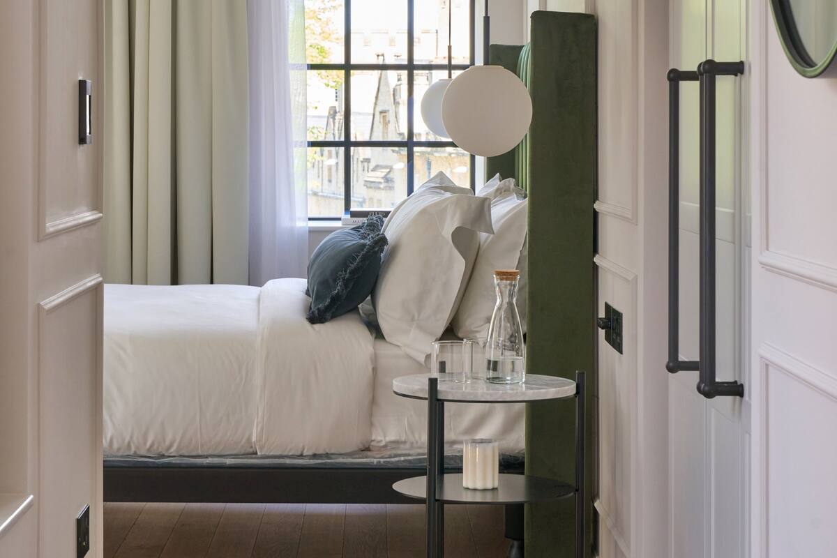 A bedroom with a bed, bedside table, and a window with curtains.