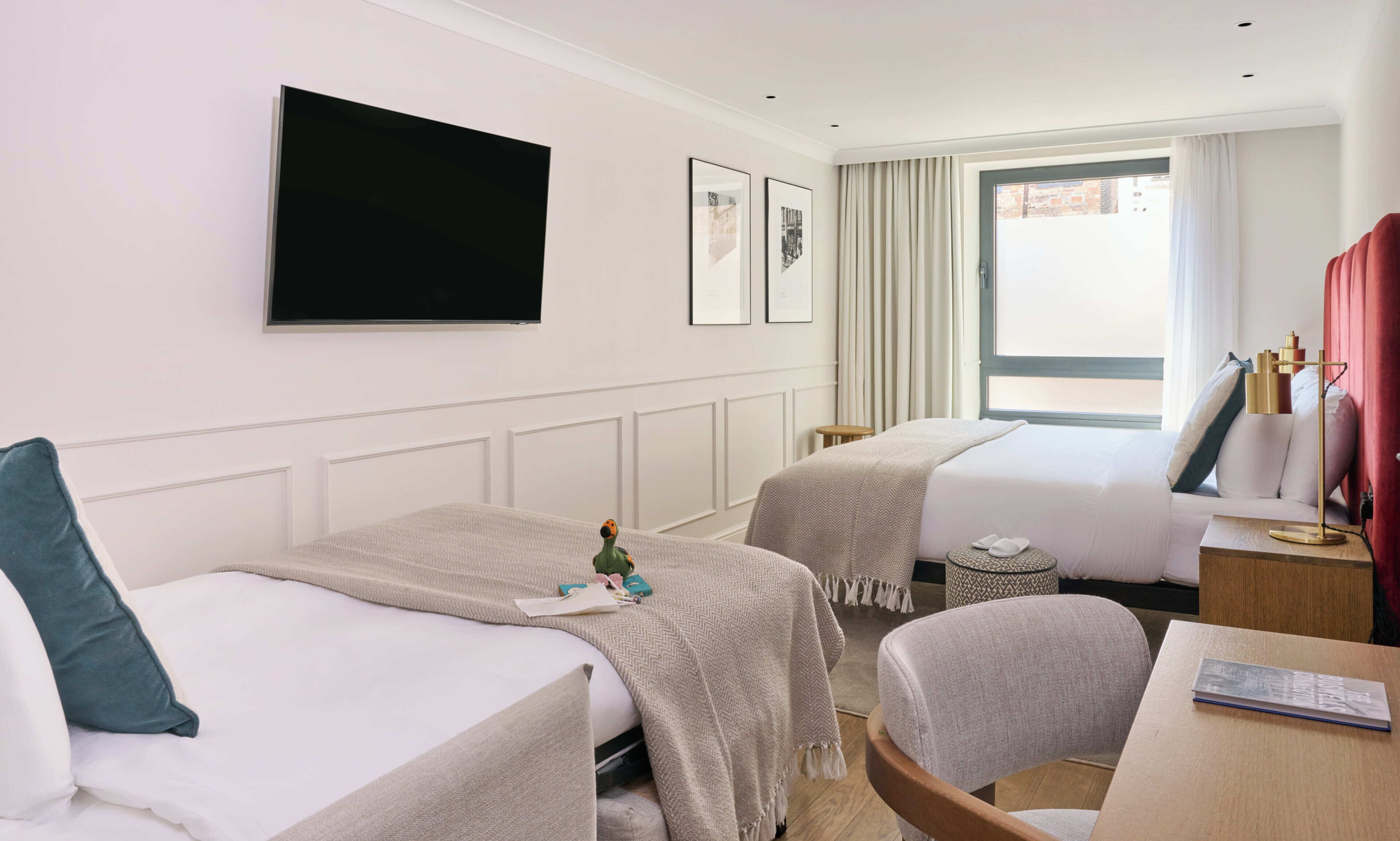 A hotel room with two beds, a TV, a desk, and a chair.