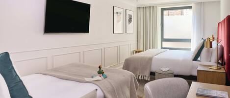 A hotel room with two beds, a TV, a desk, and a chair.