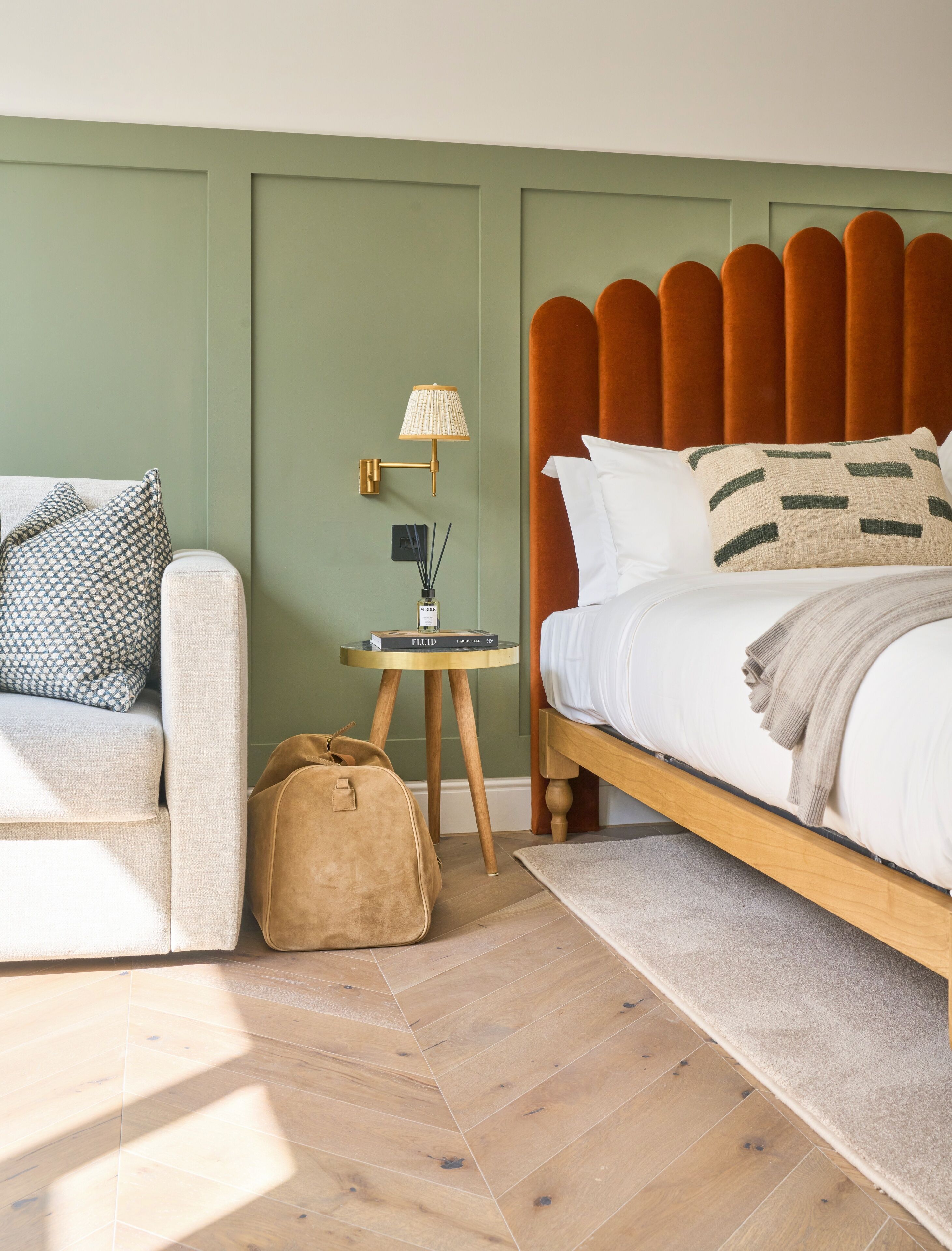A bedroom with a bed, a nightstand, a lamp, a chair, and a bag.