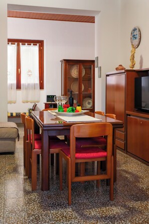 A dining area with a wooden table, chairs, and a television on a cabinet.