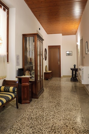 A hallway with a wooden ceiling, a cabinet with glass doors, a door, a radiator, and a patterned carpet. - Annalú Vacation Home (I.U.N. R5074) (Orosei)