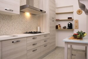A modern kitchen with a gas stove, wooden cabinets, and a tiled backsplash. - Annalú Vacation Home (I.U.N. R5074) (Orosei)