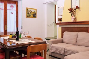 A dining area with a wooden table, chairs, a bottle of wine, and two wine glasses. - Annalú Vacation Home (I.U.N. R5074) (Orosei)