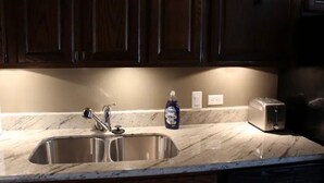 A kitchen with a stainless steel sink, a bottle of dish soap, and a toaster on the counter.